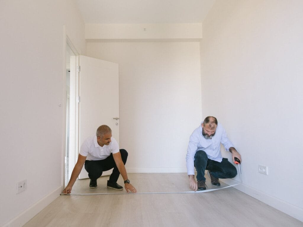 two men measuring length of the empty room with white walls rental property in Land O' Lakes